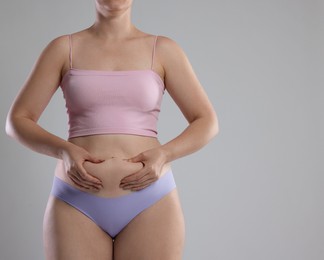 Photo of Liposuction. Woman in underwear touching her belly on grey background, closeup. Space for text