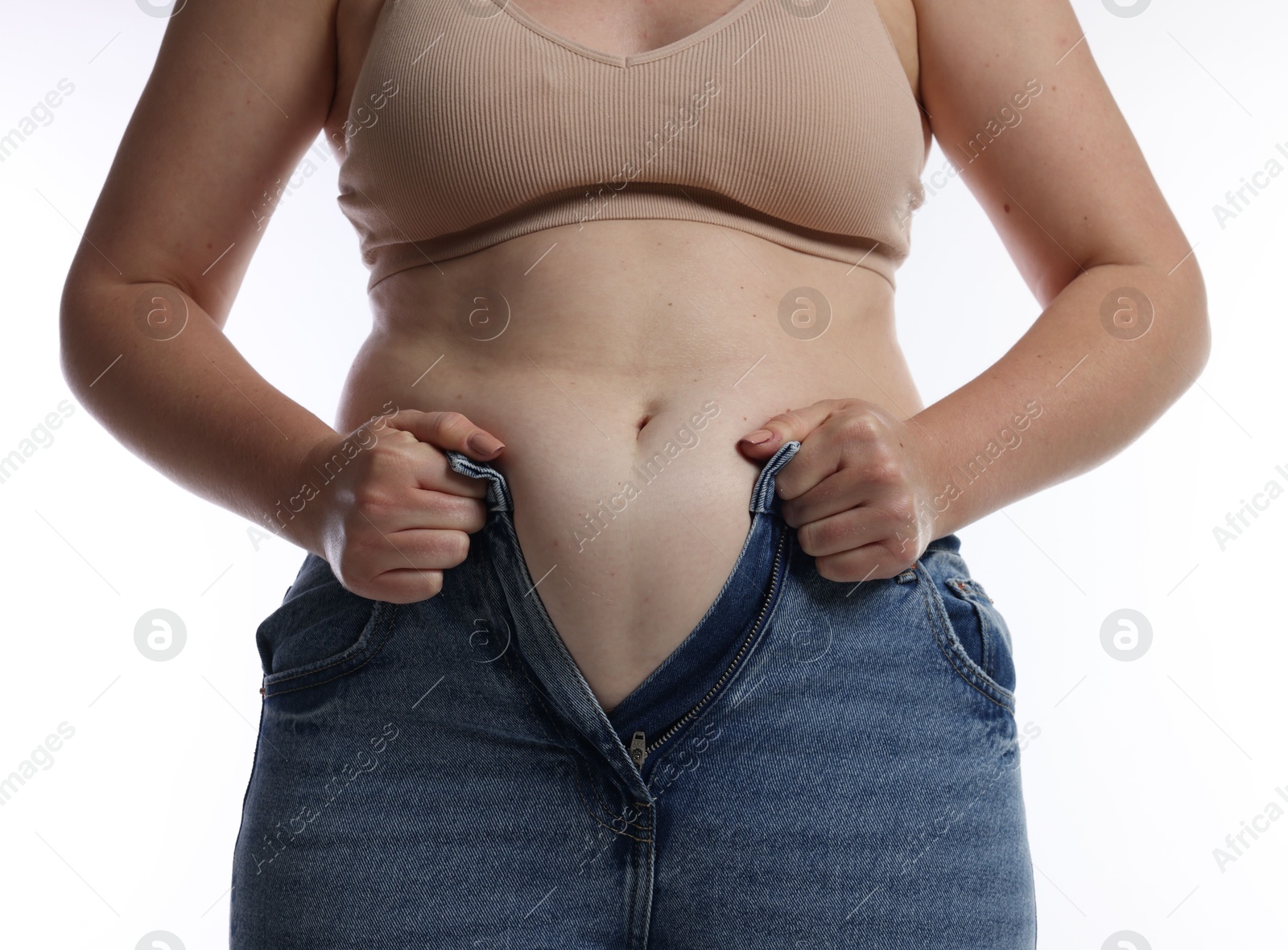 Photo of Liposuction. Woman trying to put on tight jeans against white background, closeup
