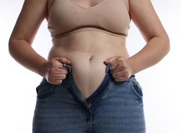 Photo of Liposuction. Woman trying to put on tight jeans against white background, closeup