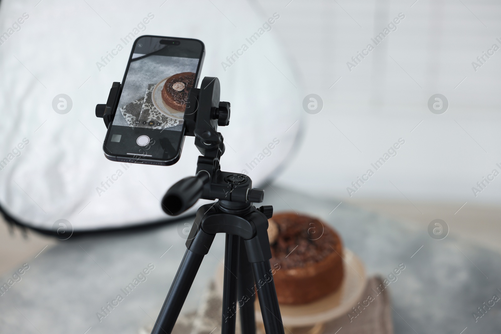 Photo of Shooting chocolate cake with smartphone in studio, selective focus. Professional food photography