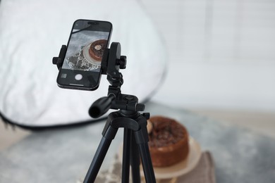 Photo of Shooting chocolate cake with smartphone in studio, selective focus. Professional food photography