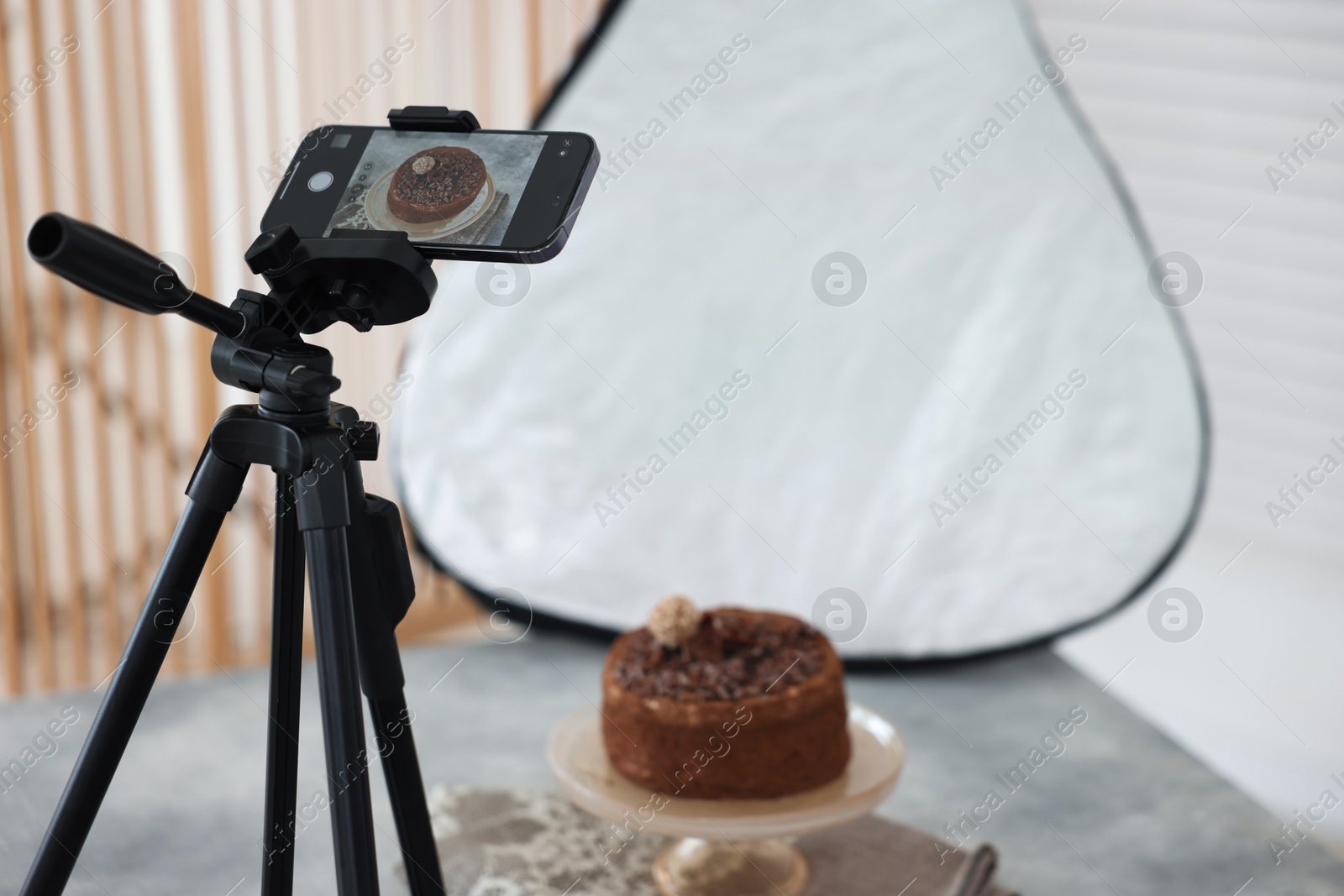 Photo of Shooting chocolate cake with smartphone in studio, selective focus. Professional food photography