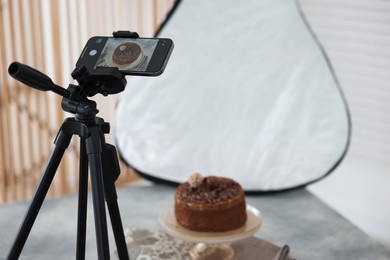 Photo of Shooting chocolate cake with smartphone in studio, selective focus. Professional food photography