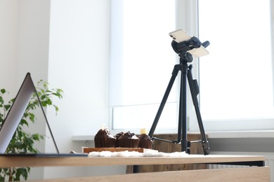 Photo of Shooting chocolate muffins with smartphone in studio. Professional food photography