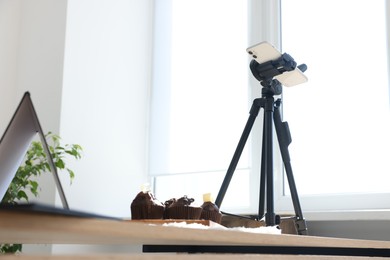 Photo of Shooting chocolate muffins with smartphone in studio, low angle view. Professional food photography