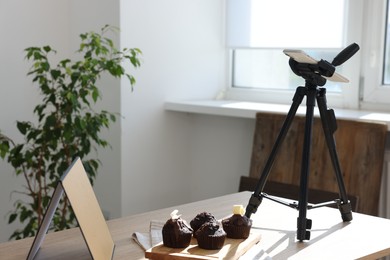 Photo of Shooting chocolate muffins with smartphone in studio. Professional food photography
