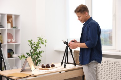 Photo of Man taking picture of chocolate muffins in studio. Professional food photography
