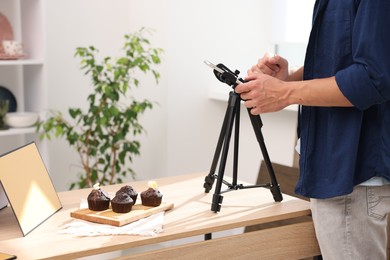Photo of Man taking picture of chocolate muffins in studio, closeup. Professional food photography