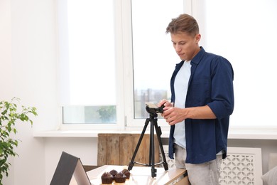 Photo of Man taking picture of chocolate muffins in studio. Professional food photography