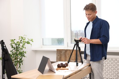 Photo of Man taking picture of chocolate muffins in studio. Professional food photography