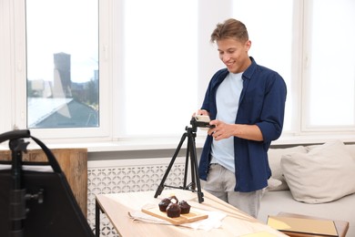 Photo of Man taking picture of chocolate muffins in studio. Professional food photography