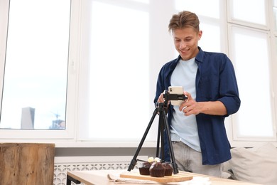 Photo of Man taking picture of chocolate muffins in studio. Professional food photography