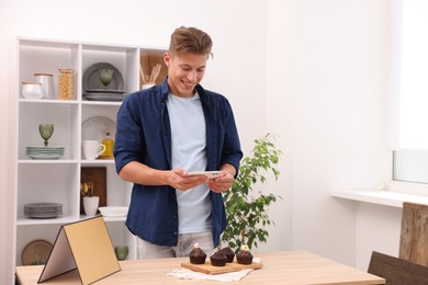 Photo of Man taking picture of chocolate muffins in studio. Professional food photography