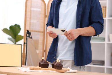 Photo of Man taking picture of chocolate muffins in studio, closeup. Professional food photography