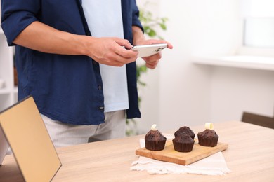 Photo of Man taking picture of chocolate muffins in studio, closeup. Professional food photography