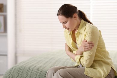 Photo of Young woman suffering from stomachache at home, space for text