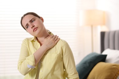 Photo of Young woman suffering from neck pain at home
