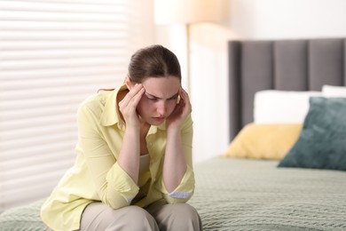 Photo of Young woman suffering from headache at home, space for text
