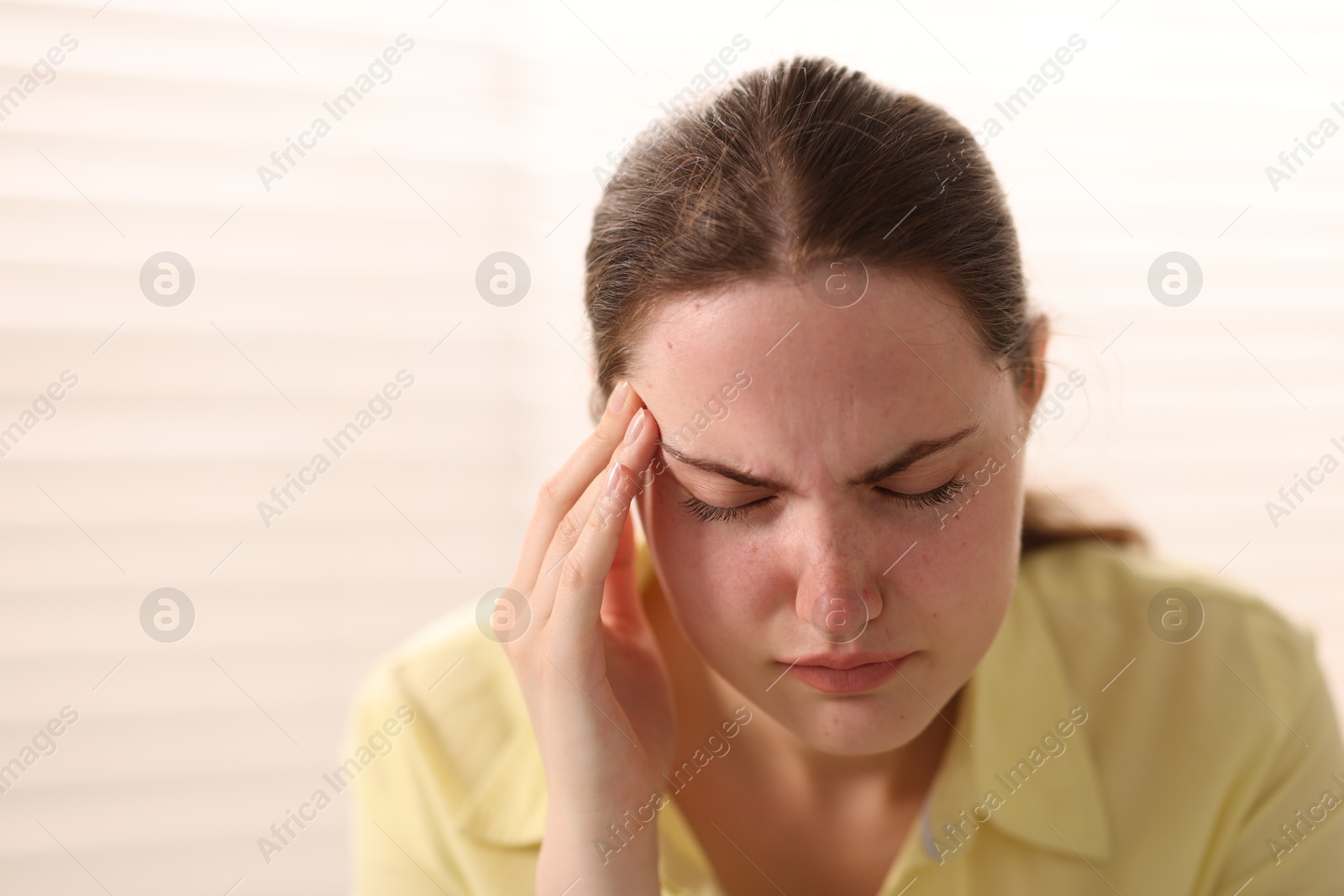 Photo of Young woman suffering from headache at home, space for text