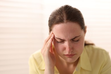 Photo of Young woman suffering from headache at home, space for text