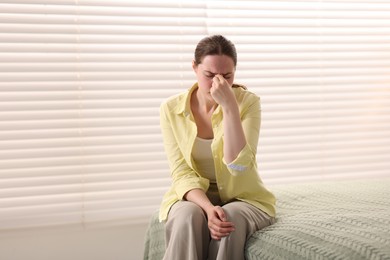 Photo of Young woman suffering from headache at home
