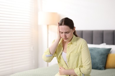 Photo of Young woman suffering from headache at home, space for text