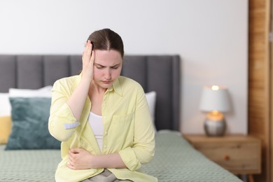 Photo of Young woman suffering from headache at home, space for text