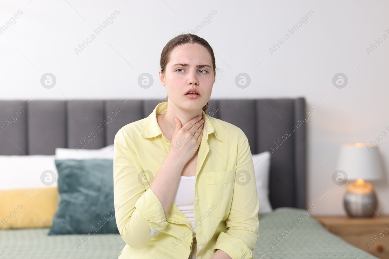 Photo of Young woman suffering from sore throat at home