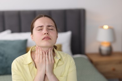 Photo of Young woman suffering from sore throat at home, space for text