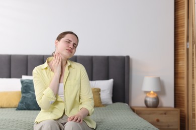 Photo of Young woman suffering from sore throat at home, space for text