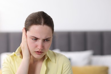Photo of Young woman suffering from headache at home, space for text