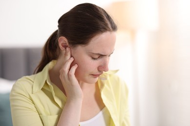 Photo of Young woman suffering from headache at home, space for text