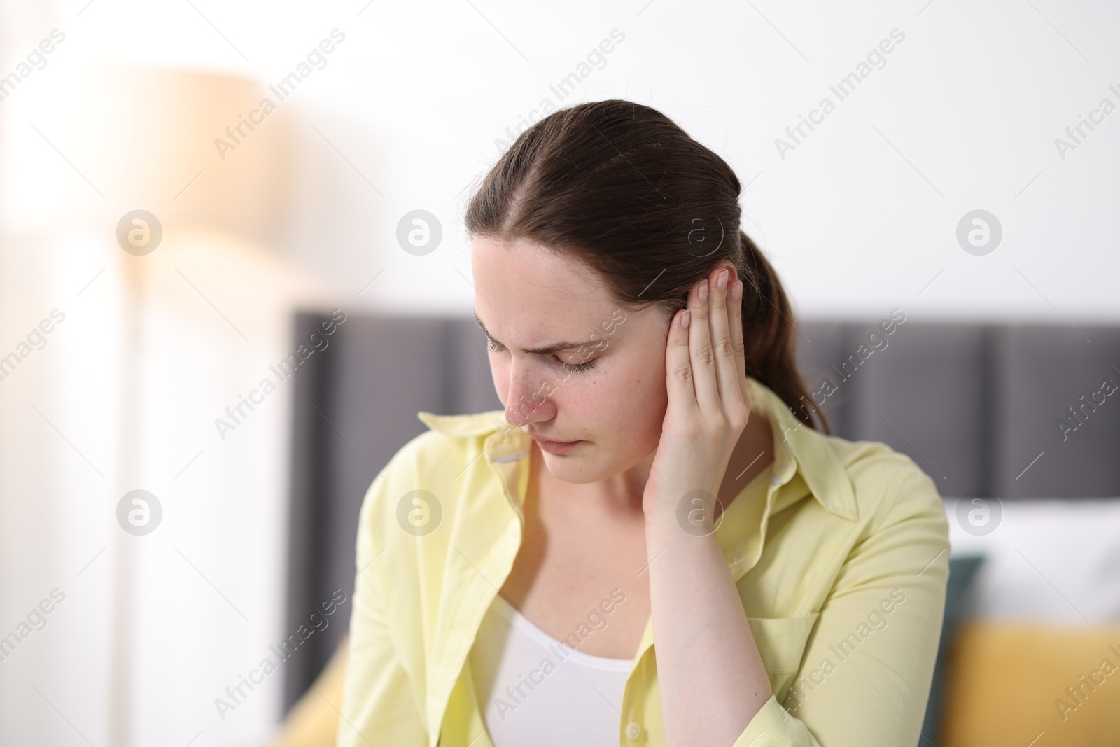 Photo of Young woman suffering from headache at home