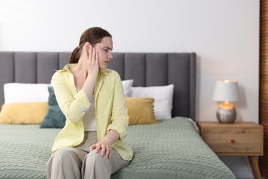Photo of Young woman suffering from headache at home, space for text