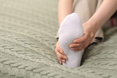 Photo of Young woman suffering from foot pain at home, closeup. Space for text