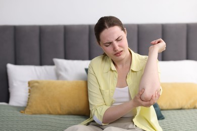 Photo of Young woman suffering from elbow pain at home