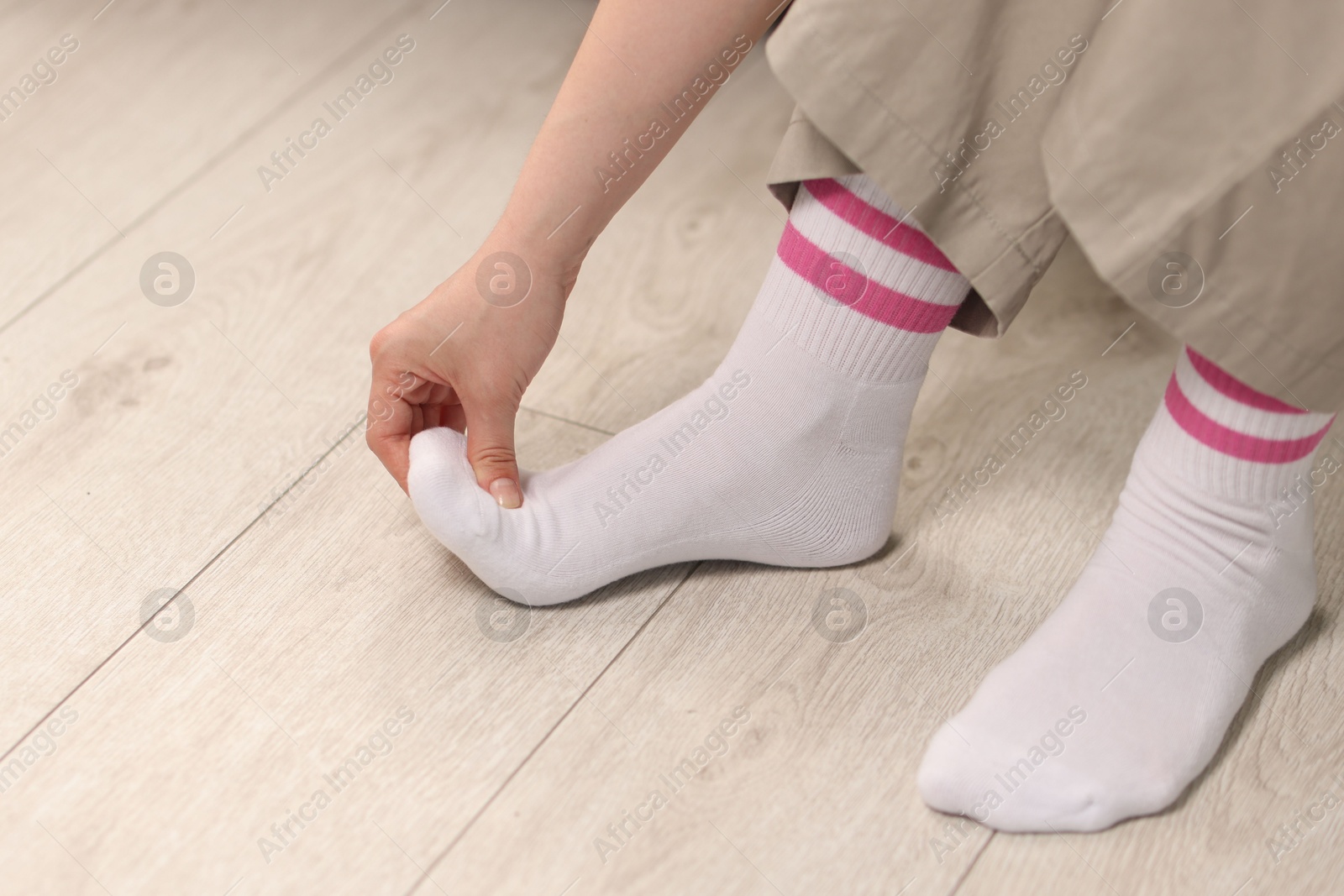 Photo of Young woman suffering from foot pain at home, closeup