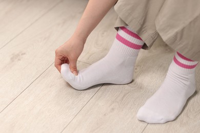 Photo of Young woman suffering from foot pain at home, closeup
