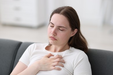 Photo of Young woman suffering from chest pain at home