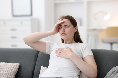 Photo of Young woman suffering from chest pain at home
