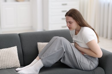 Photo of Young woman suffering from stomachache at home