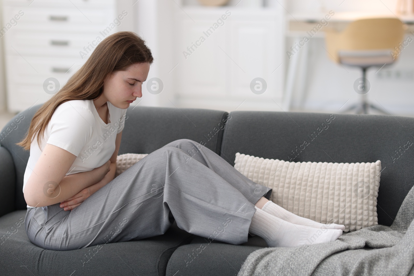Photo of Young woman suffering from stomachache at home