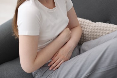 Photo of Young woman suffering from stomachache at home, closeup