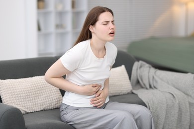 Photo of Young woman suffering from stomachache at home