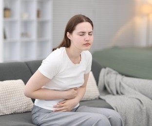 Photo of Young woman suffering from stomachache at home