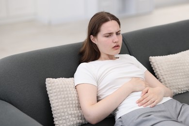 Photo of Young woman suffering from stomachache at home