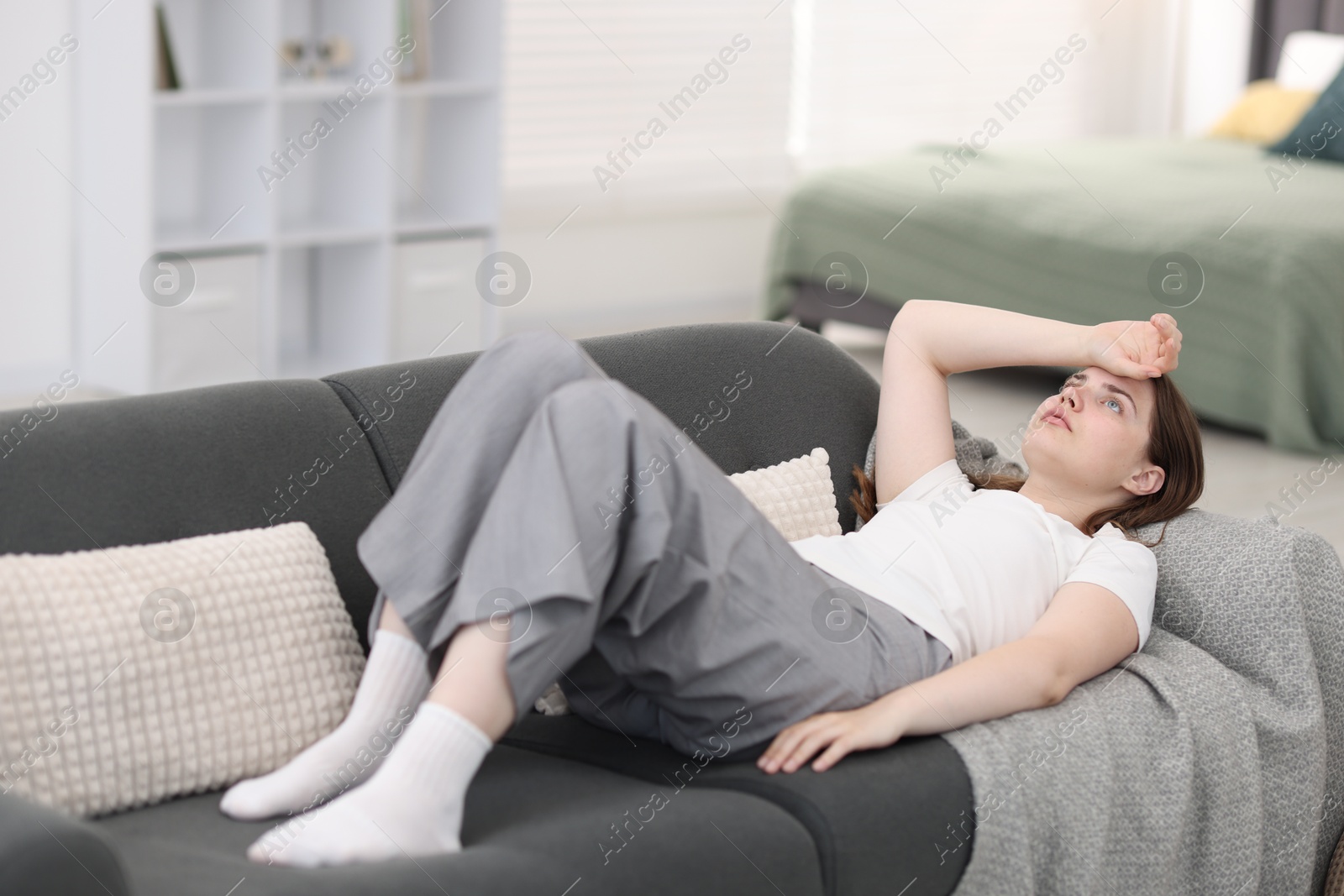 Photo of Young woman suffering from headache at home