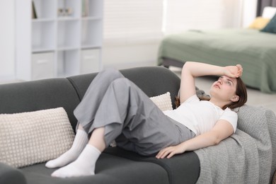 Photo of Young woman suffering from headache at home