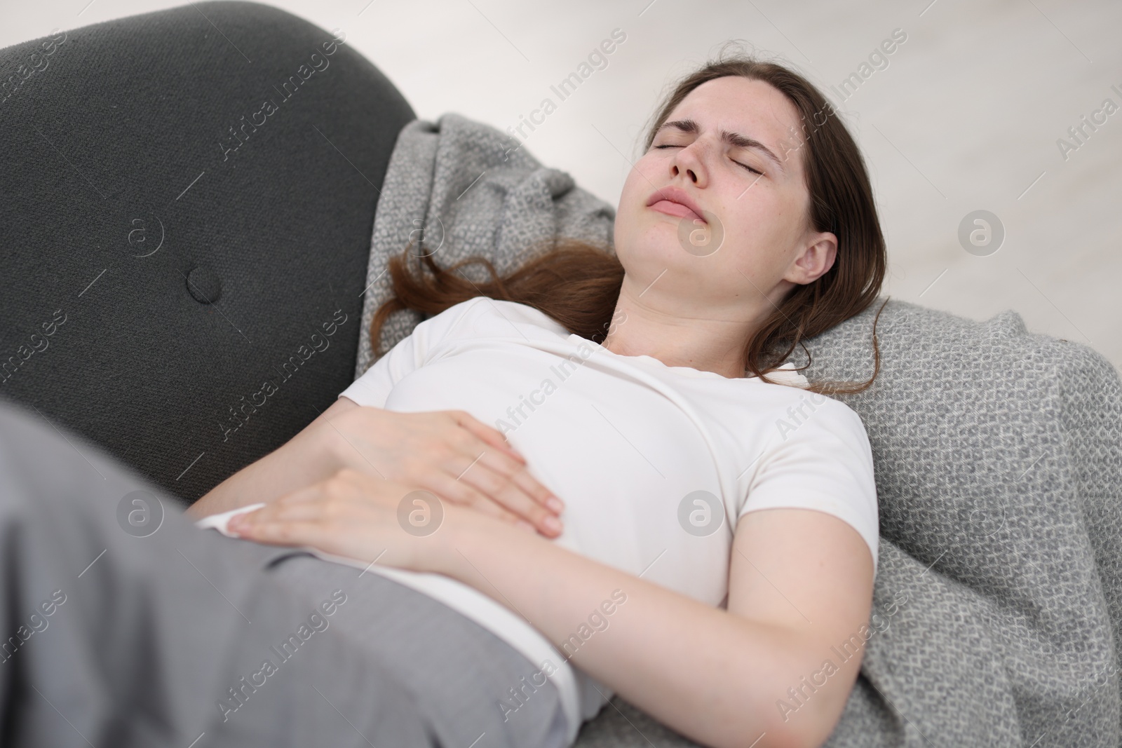 Photo of Young woman suffering from stomachache at home