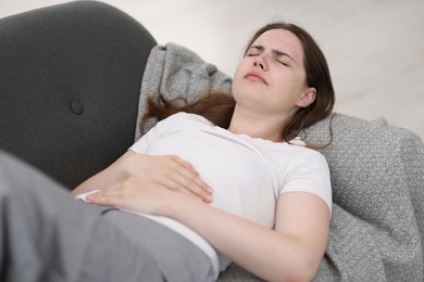 Photo of Young woman suffering from stomachache at home